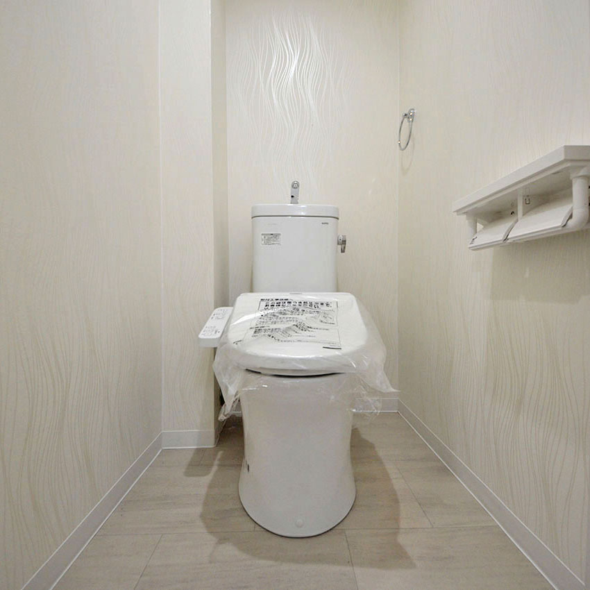 トイレは清潔感のある白でまとめています。クロスはジオメトリック柄の白いクロスで変化をつけました。