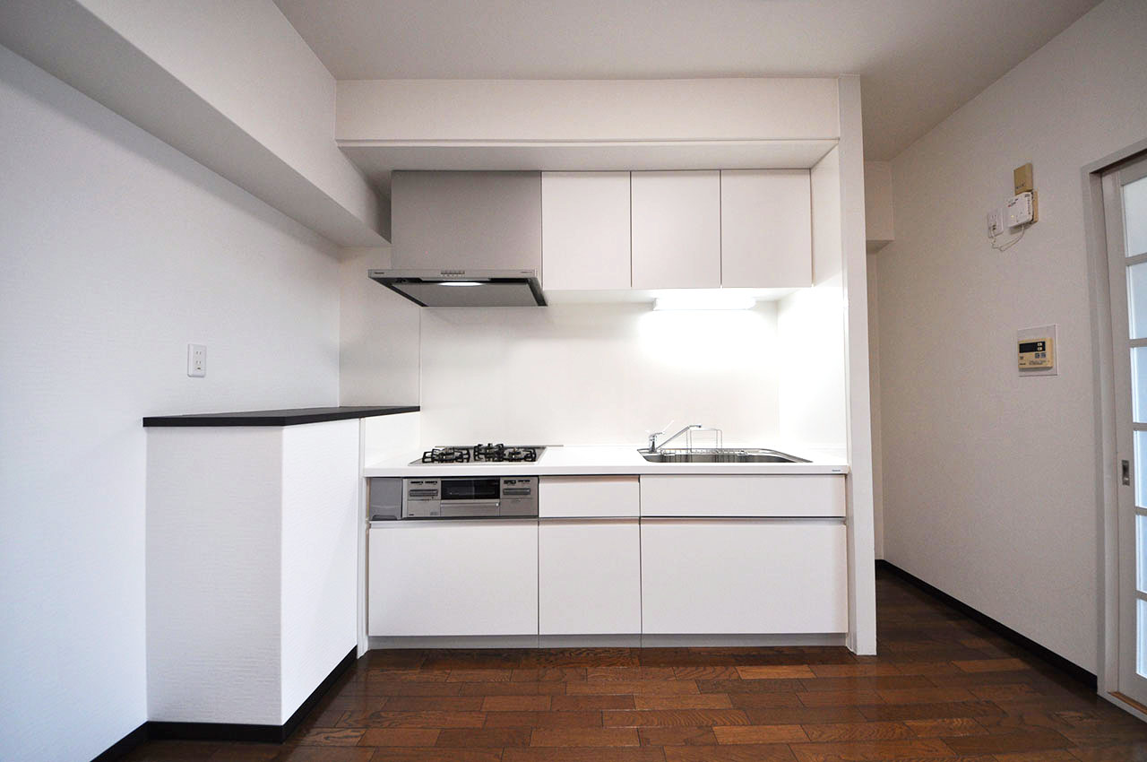 清潔感のある白いシステムキッチン。サイドには家電や調味料などを置ける棚カウンター付きです。