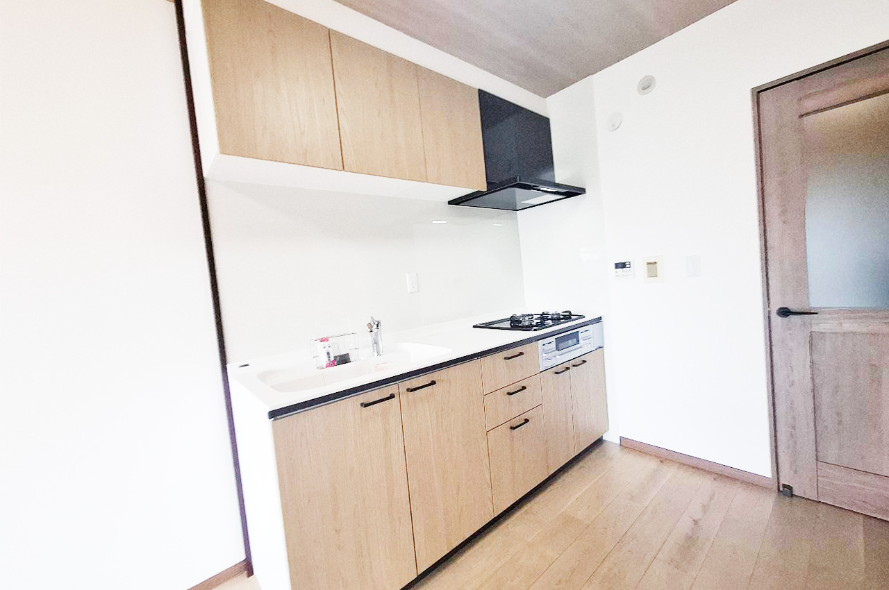 木目調の扉が温かみを演出するシステムキッチン。生活感を抑えたすっきりした空間です。