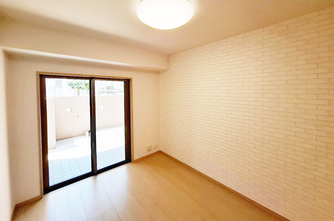 洋室②:レンガ調のアクセントクロスに貼替えあたたかみを演出。テラスに面しており採光も良好。