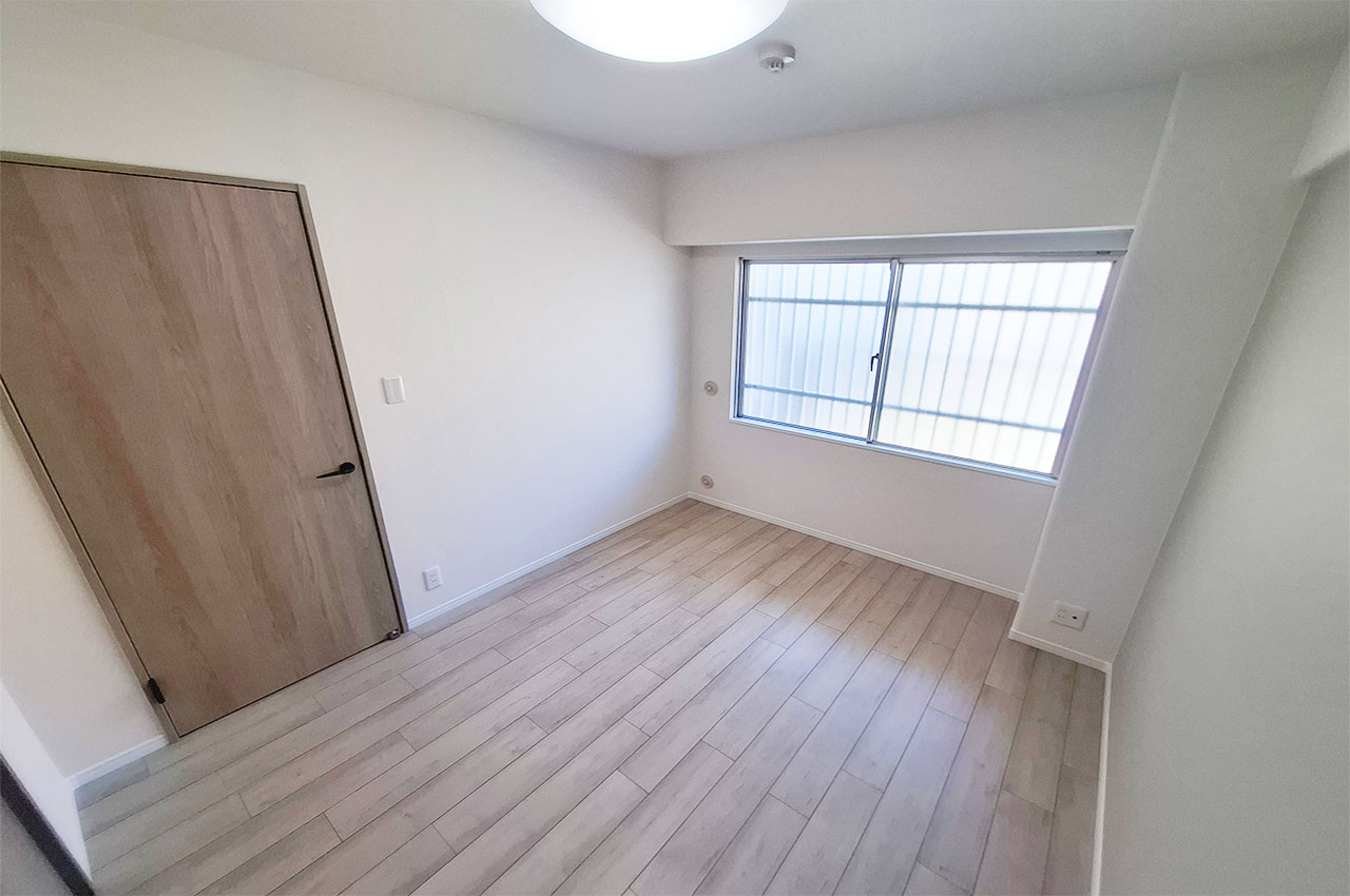 リフォームできれいになった約5.4帖の洋室①。落ち着いたグレーのアクセントクロスを施しました。