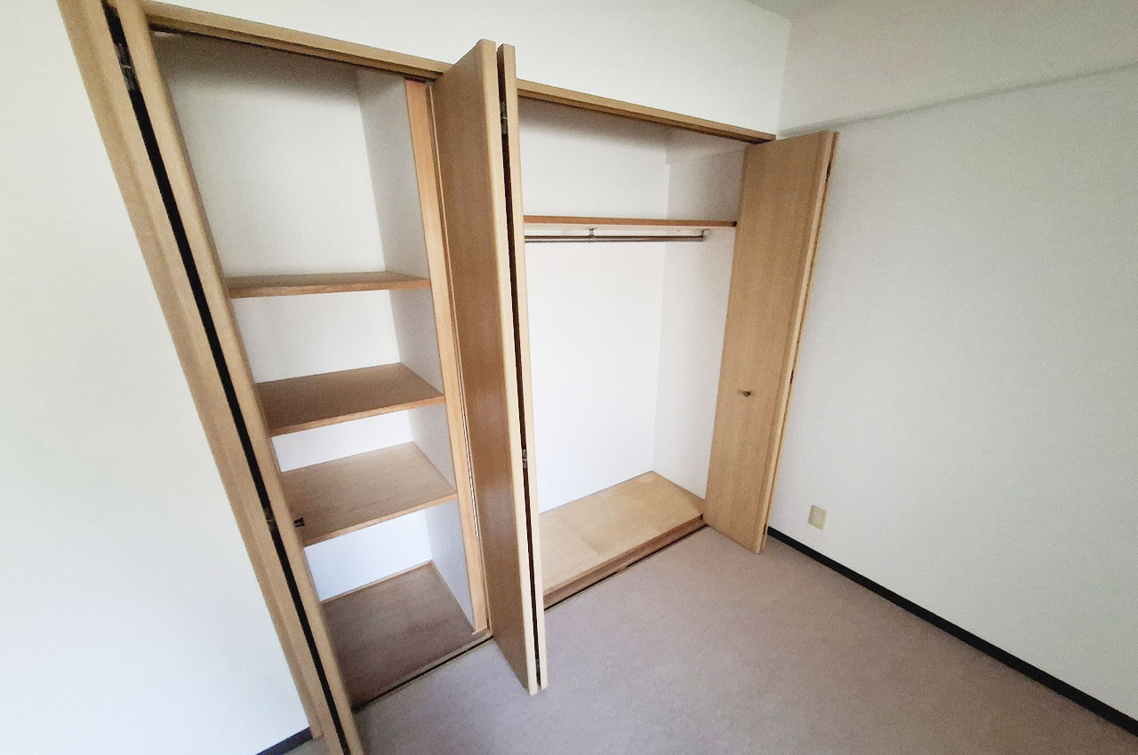 洋室内の棚収納と、ハンガーパイプのあるクローゼットの機能的な収納。