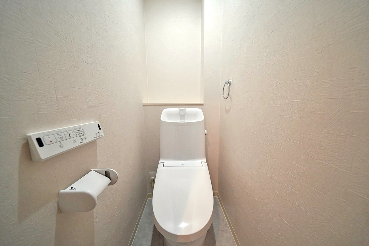 温水洗浄便座付きの清潔感あるトイレ。落ち着いた色合いでリラックスできる空間です。