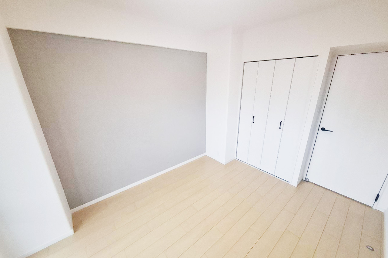 リフォームできれい生まれ変わった約6.3帖の洋室①。グレーのアクセントクロスが映える一室です。