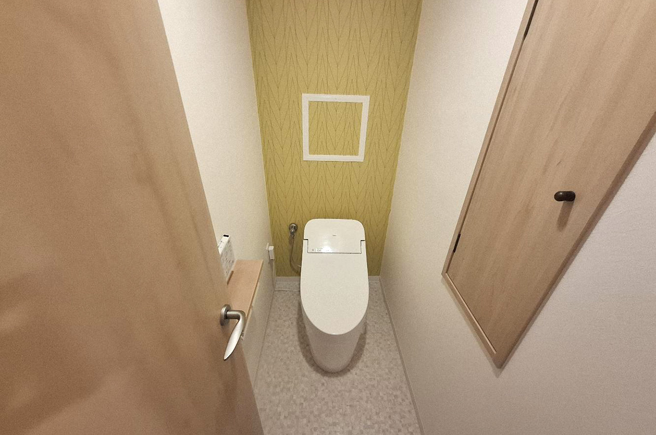 トイレ内の壁や床、入口建具は新調済み。明るいイエローのアクセントクロスが印象的です。